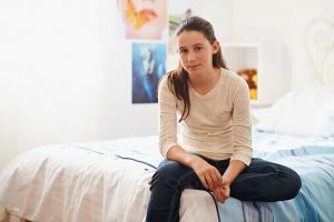 teen girl sits on bed in bedroom avoiding entering teen drug abuse statistics
