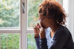 woman sits by window thinking about a vicodin addiction treatment center