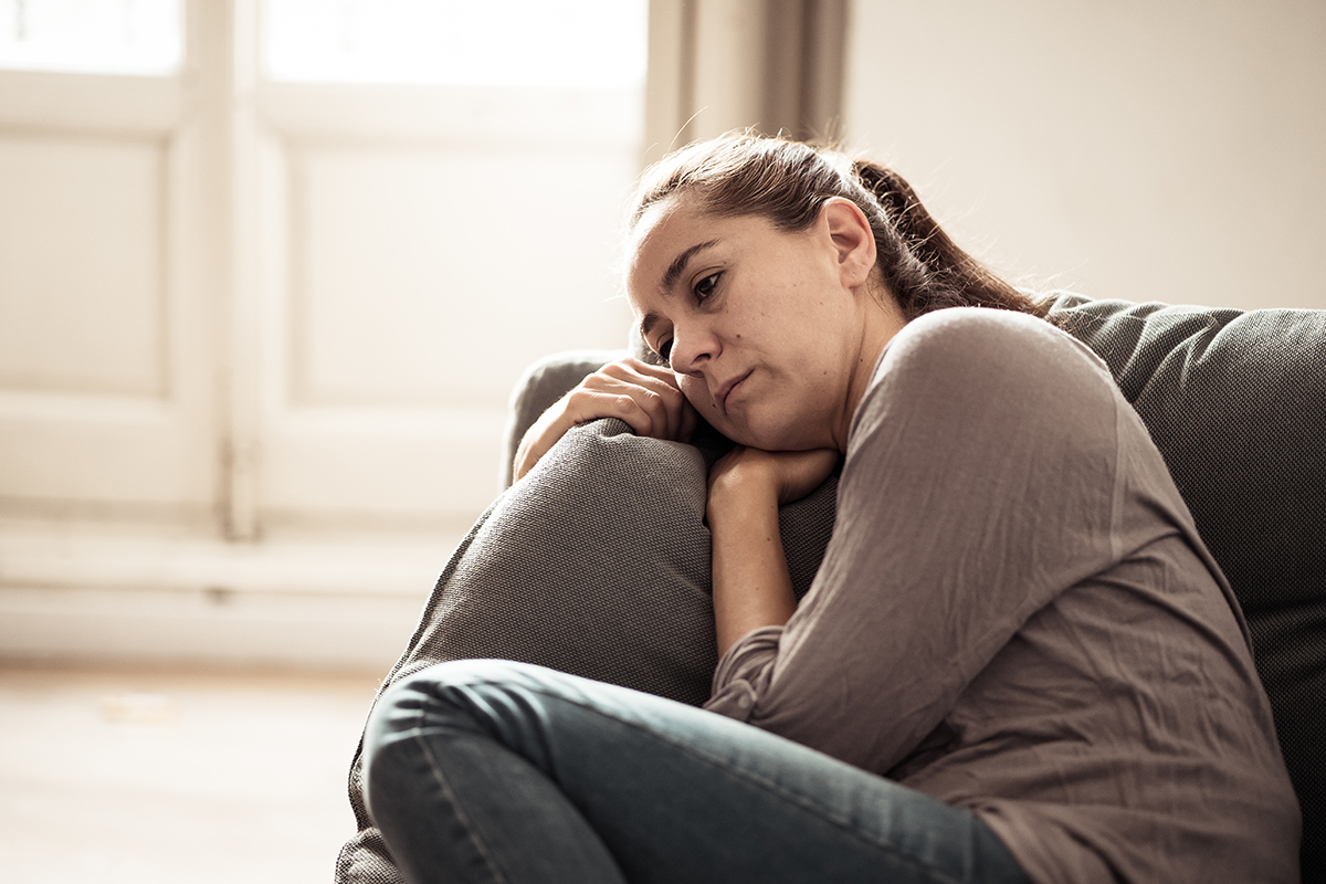 woman curls up with a pillow on couch while wondering what is psychological dependence