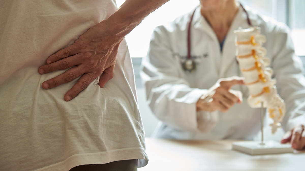 doctor explaining what is pain management while patient holds their back