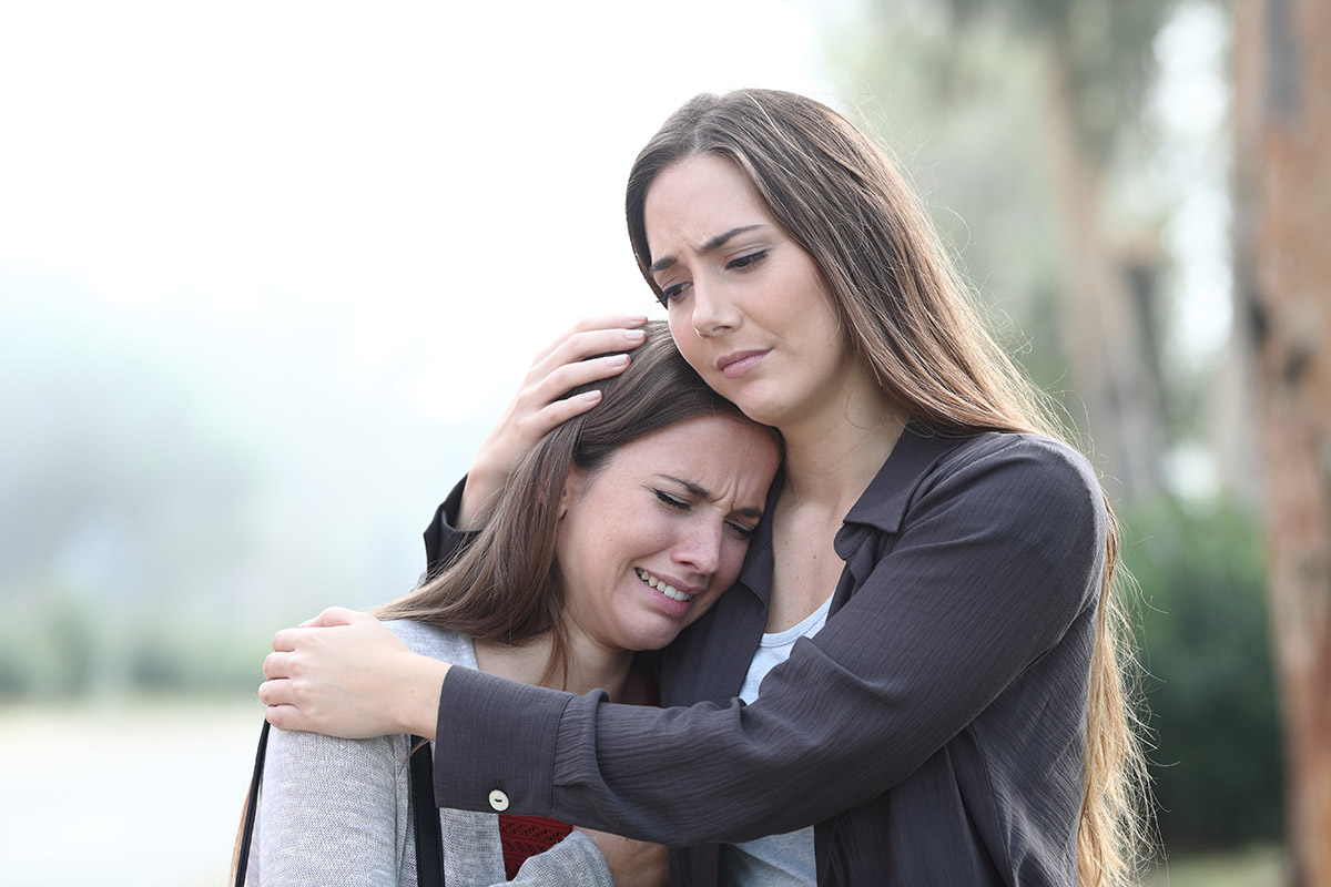 women and trauma showing as crying sisters hold each other