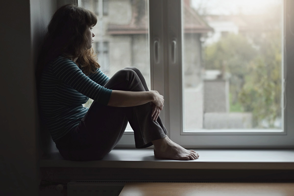 woman looking out window wondering how to navigate recovery in quarantine