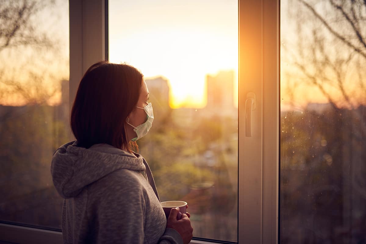 woman looking out window realizing covid-19s impact on addiction