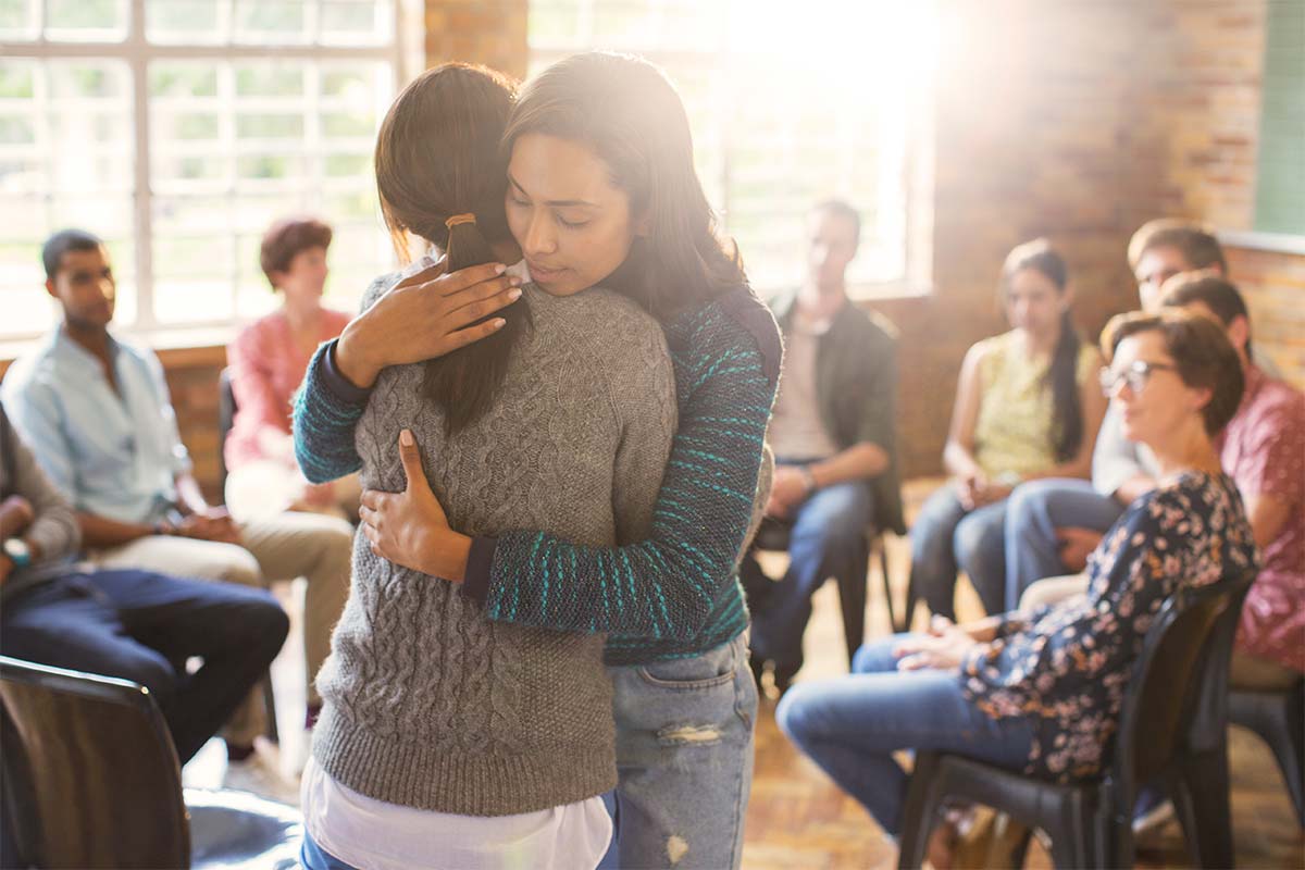 sisters hugging as they learn to be supportive during addiction recovery